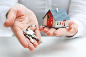Investieren in Punta Cana zwei Hände halten einen Haustürschlüssel und ein Miniaturhaus 